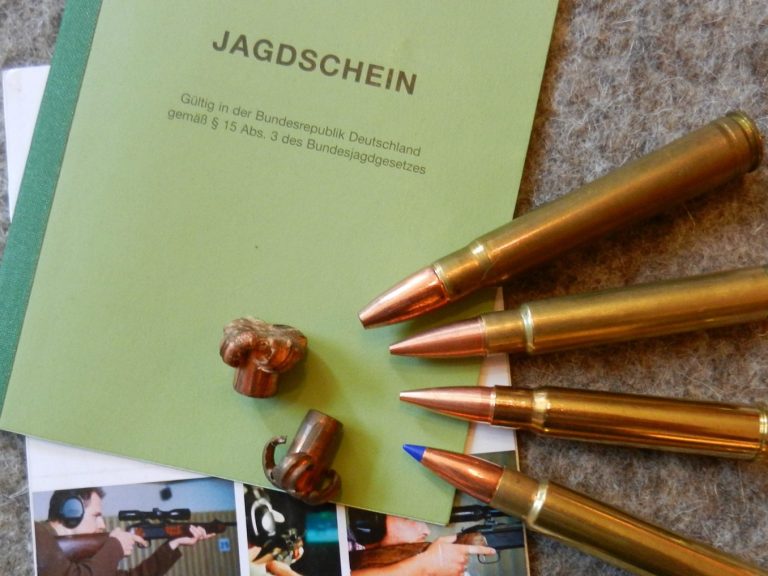 Auf einem Jagdschein liegt Gewehrmunition.