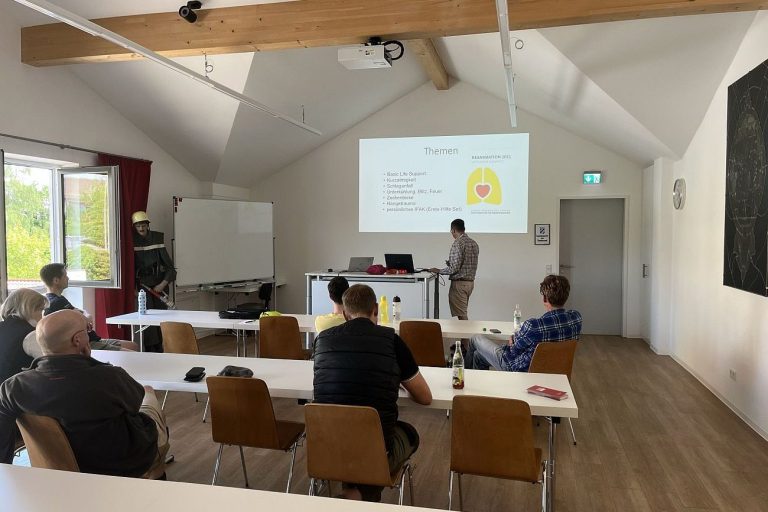 In einem Schulungsraum sitzen Lehrgangsteilnehmer und vorn unterrichtet ein Trainer.